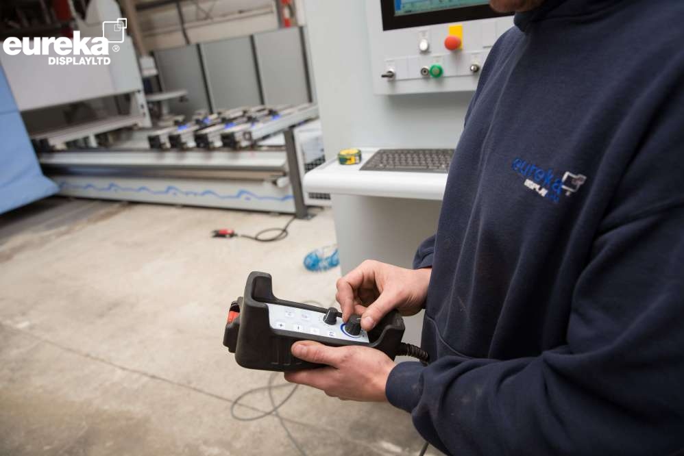 A man controling a handheld device to monitor a machine.