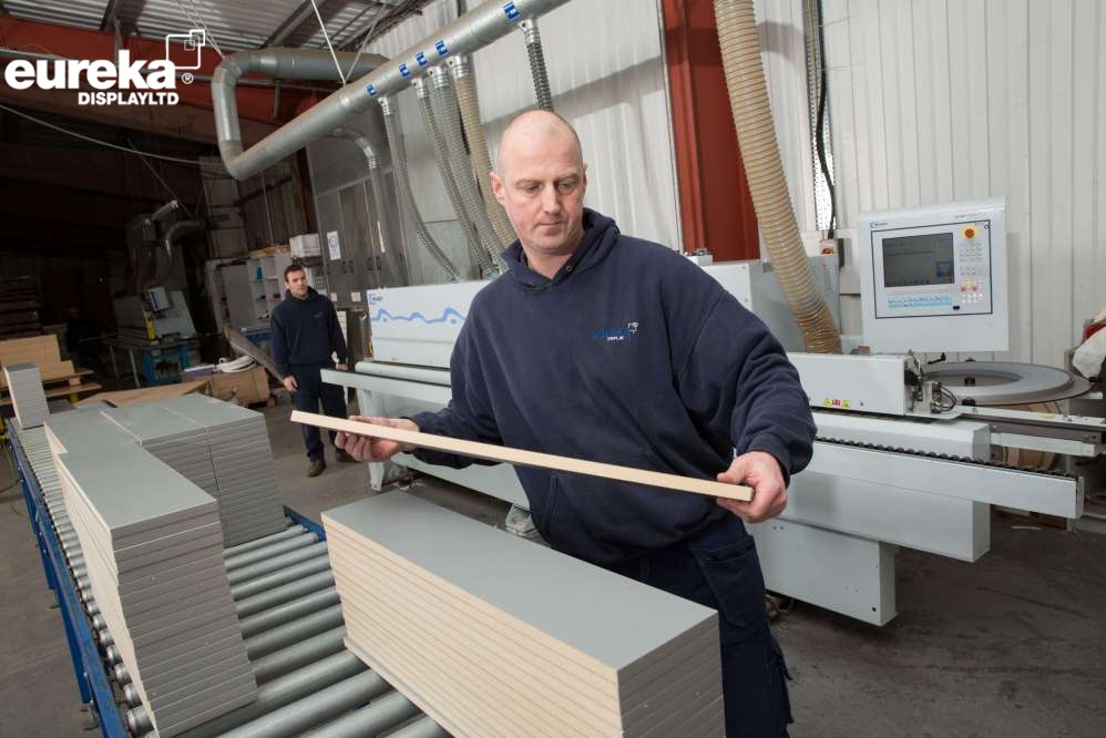 A man checking the size of the boards to make sure they are perfect.