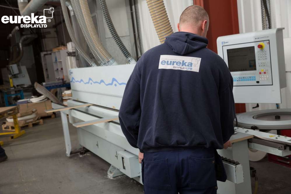 A man putting a board on a machine for it to have straightline edge banding